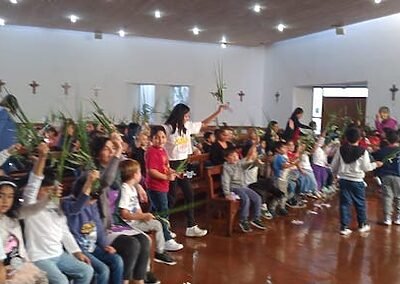 El viernes 30 de marzo vivimos la bendición de los ramos en la capilla de nuestro colegio. Así comenzamos Semana Santa, con la memoria de la entrada triunfante de Jesús a Jerusalem. Niñas, niños y jóvenes fueron llegando por niveles; primero el inicial, luego el intermedio y finalizamos con el ciclo avanzado, quienes iban ingresando cantando alegremente junto al coro el Hosana, que es tan característico del Domingo de Ramos. Luego veían un video con el relato de Jesús entrando en medio de una gran multitud en Jerusalem luego de haber estado en el monte Tabor orando. Muchos se preguntaban; “¿Quién es este?”, mientras que otros lo reconocían como el hijo de Dios, el que ha de venir, el que se profetizó por tanto tiempo. Finalmente se bendijeron los ramos que permanecen en nuestras casas hasta el inicio de la Cuaresma siguiente, pues se queman y se transforman en la ceniza que protagoniza el Miércoles de Ceniza. Fue una hermosa y animada jornada de fiesta e inicio de esta nueva Semana Santa.